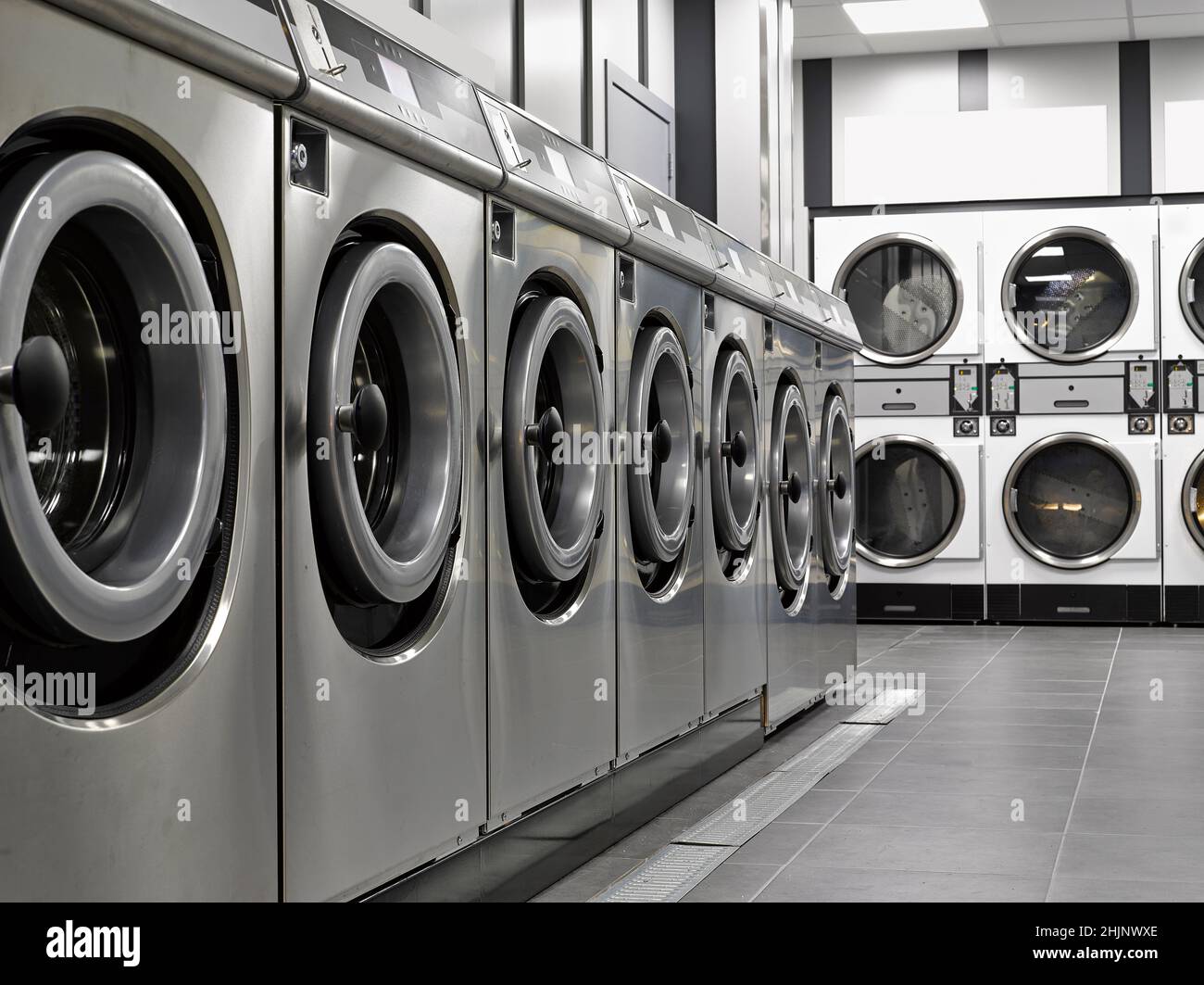 Fila di macchine lavatrici industriali in una lavanderia pubblica Foto Stock