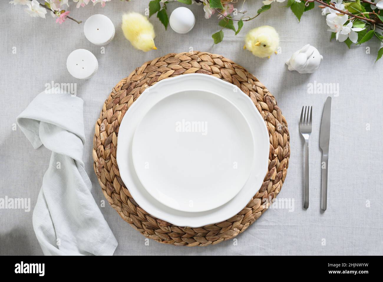 Tavolo pasquale con cazzo, decorazioni gialle, fiori freschi e uova. Cena di eleganza a casa. Vista dall'alto. Tradizione religiosa cristiana. Foto Stock