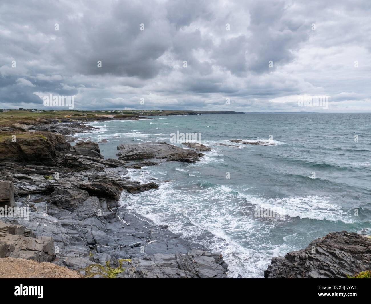 Una vista sull'Oceano Atlantico sulla costa rocciosa della Cornovaglia Nord vicino alla Baia di Treyarnon che mostra il mare, le onde e un cielo grigio argente in estate nel Regno Unito Foto Stock