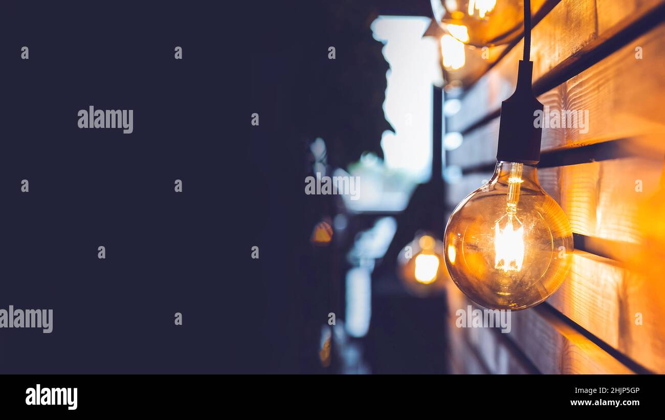 Lampadina appesa su una parete in legno a doghe. Invito all'evento con spazio per la copia. Foto Stock