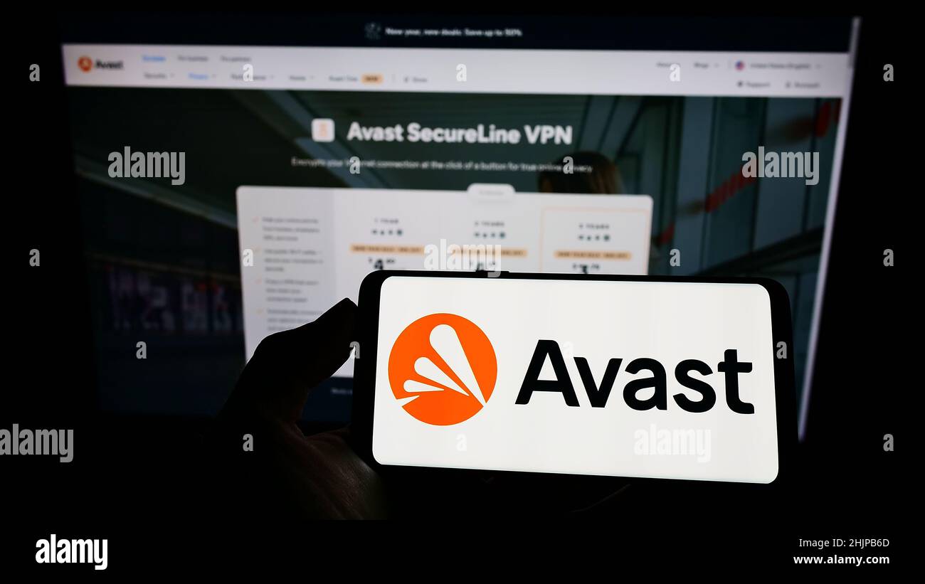Persona che tiene il cellulare con il logo della società di sicurezza informatica Avast Software s.r.o. sullo schermo di fronte al sito web aziendale. Mettere a fuoco sul display del telefono. Foto Stock