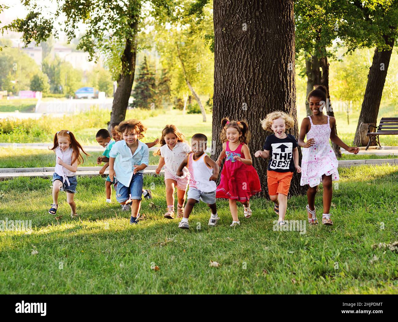 Un gruppo di preschoolers che corrono sull'erba nel Parco. Foto Stock