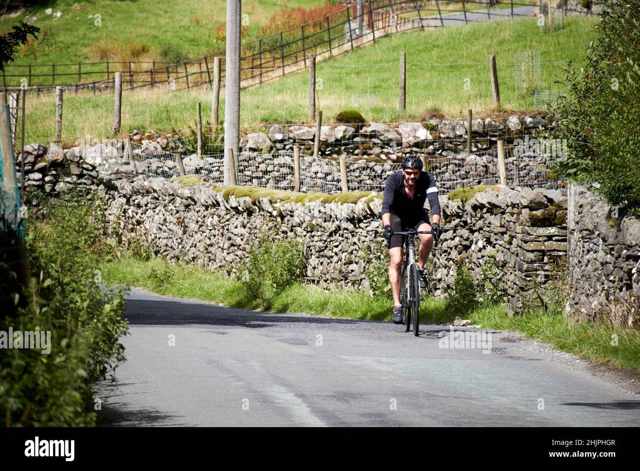 ciclista single maschio in bicicletta b5343 strada locale piccola stretta che passa attraverso la valle di langdale, distretto del lago, cumbria, inghilterra, regno unito Foto Stock