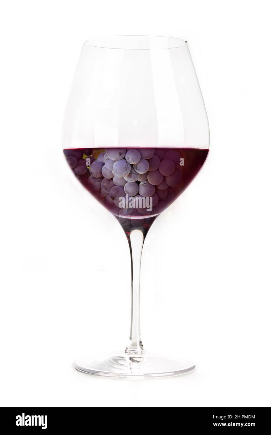 Uva da vino rosso, viola scuro, in un bicchiere, collage creativo. Classico bicchiere di vino, isolato su sfondo bianco Foto Stock