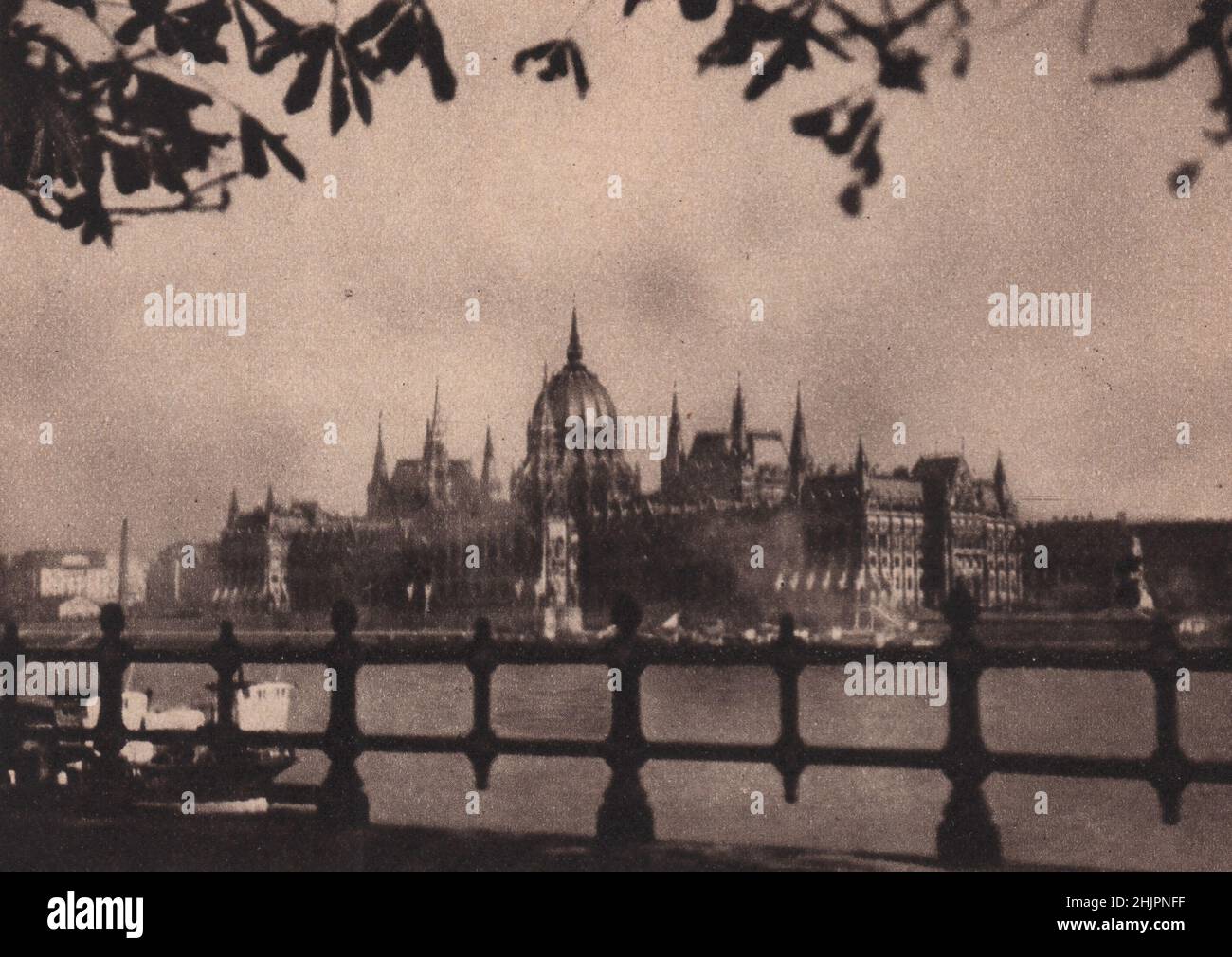 Vista attraverso il Danubio nel bagliore del tramonto la casa del Parlamento di Budapest si illumina dolcemente come un palazzo fairy di qualche miraggio delusivo. Ungheria (1923) Foto Stock