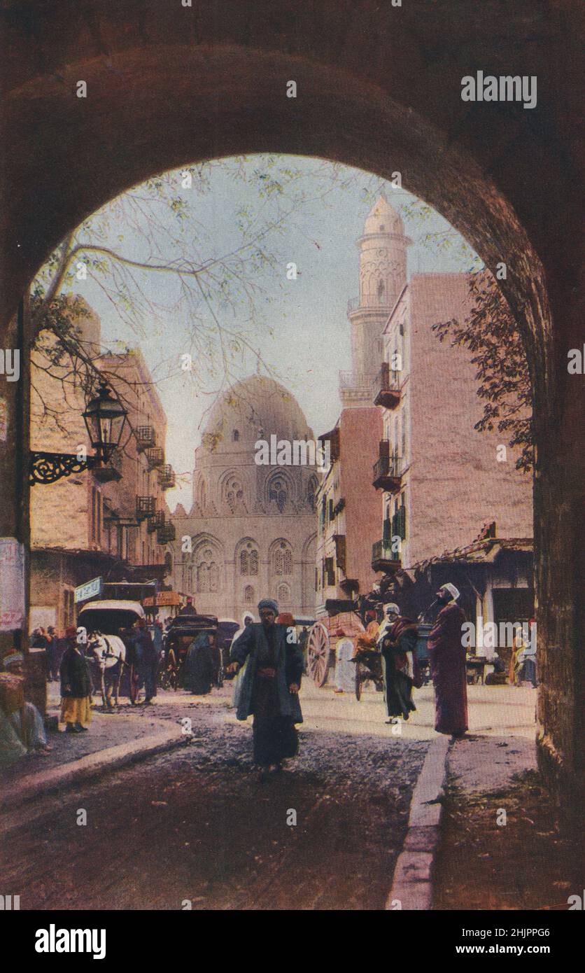 Il traffico è denso nelle strade vicino alla vecchia Università Mahomedan, la moschea El Azhar, qui incorniciata in un arco. Egitto. Cairo (1923) Foto Stock