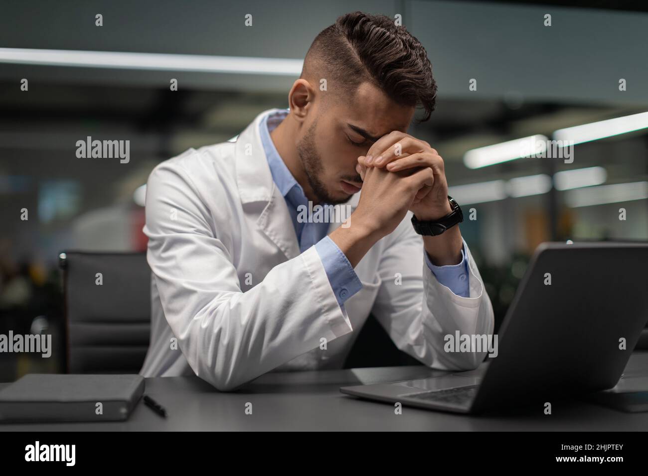 Scienziato medio-orientale esausto seduto di fronte al computer portatile Foto Stock