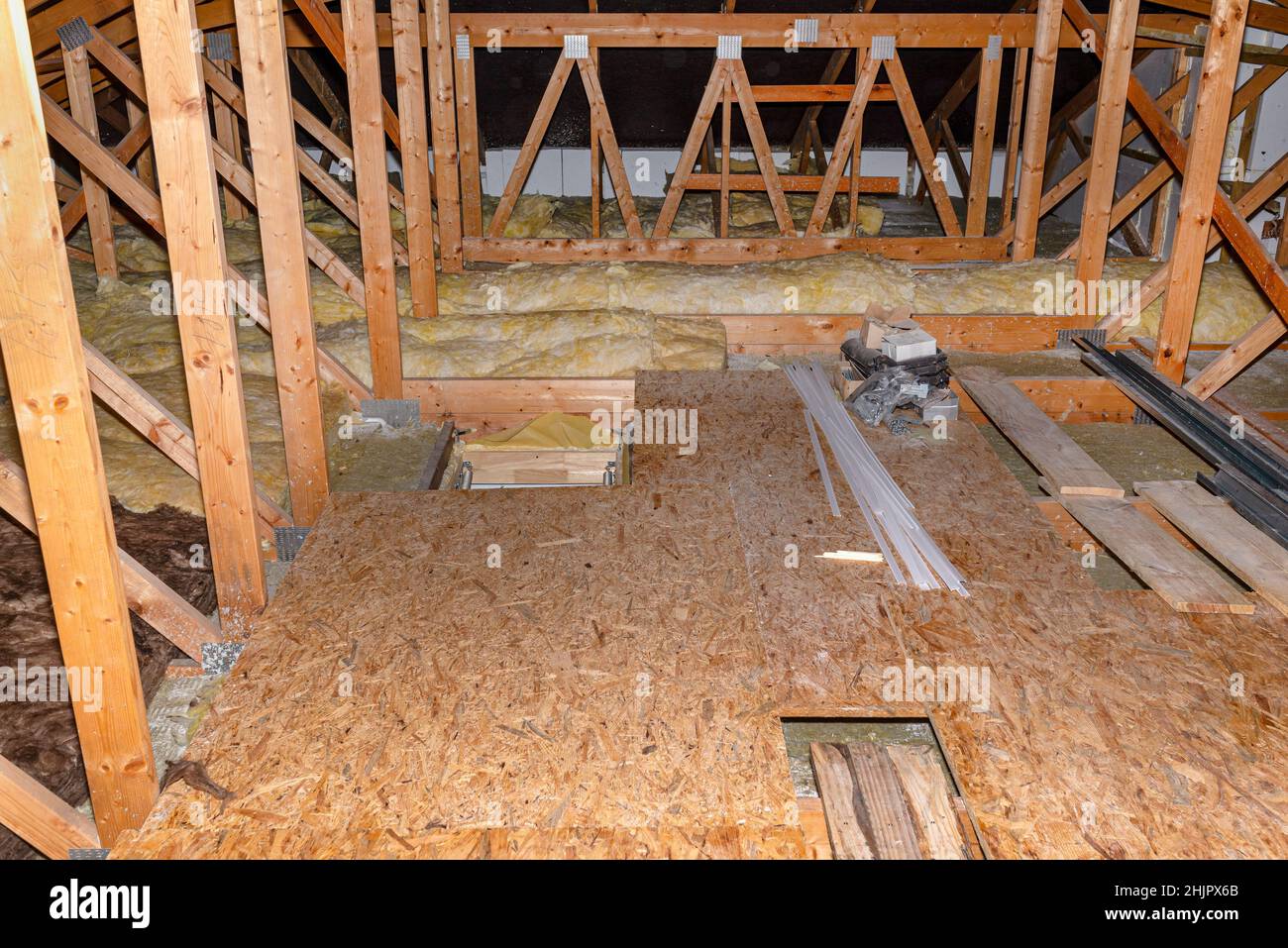 Attico non utilizzato con capriate visibili, lana minerale e pannelli OSB giacenti sulle travi del soffitto. Foto Stock