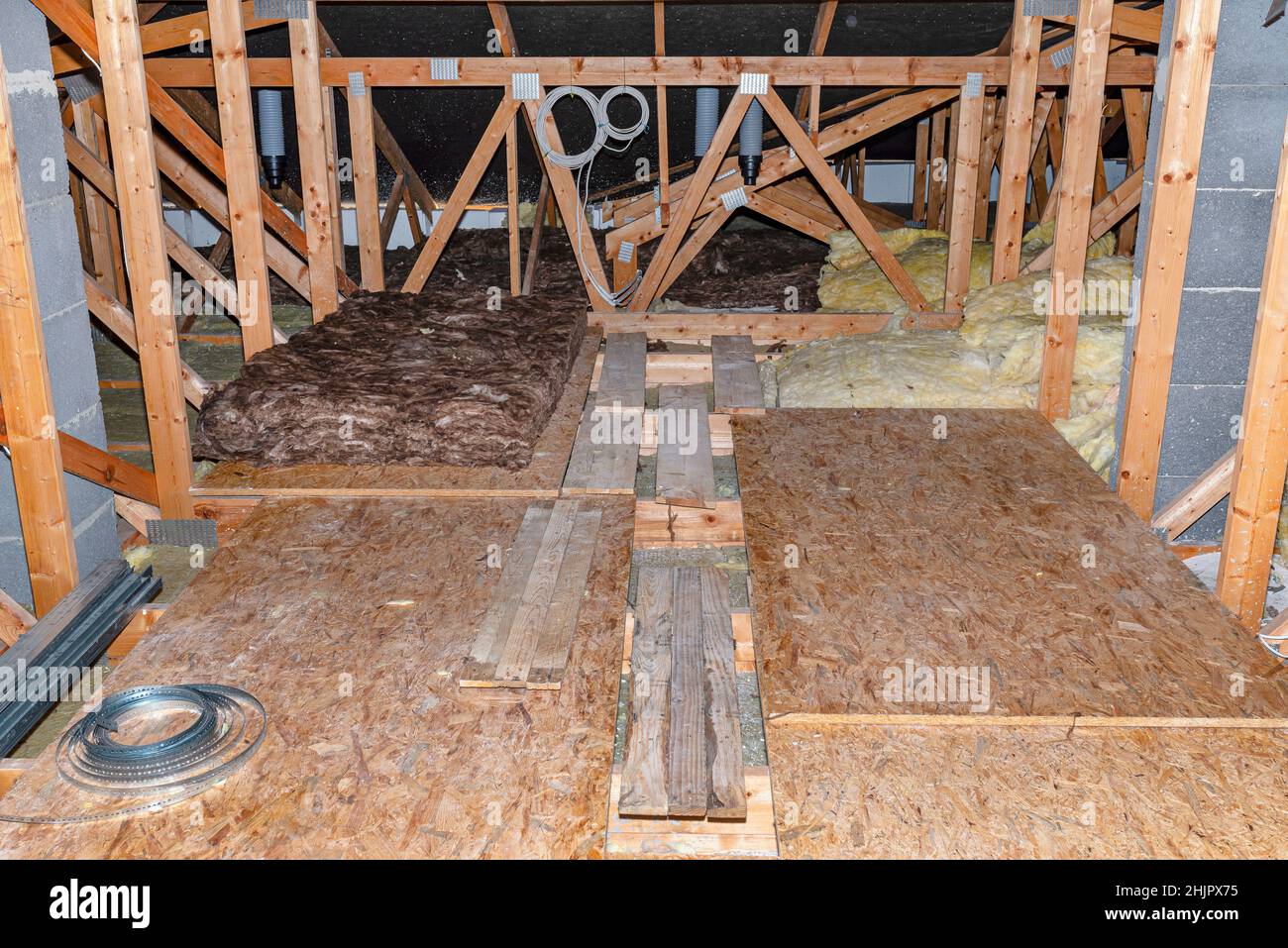 Attico non utilizzato con capriate visibili, lana minerale e pannelli OSB giacenti sulle travi del soffitto. Foto Stock