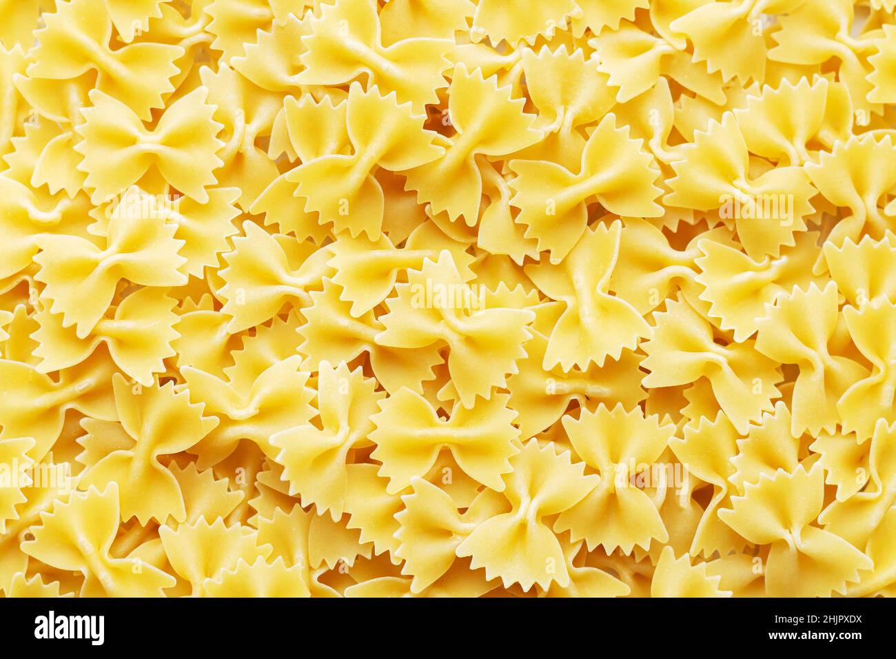Mucchio di farfalle crudo fondo di pasta italiana. Ingrediente per la cucina mediterranea Foto Stock