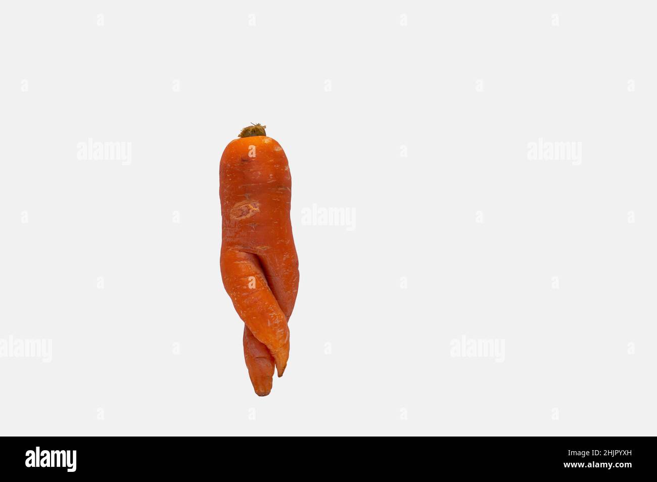 Carota deformata che assomiglia alla forma del corpo umano isolato su bianco Foto Stock