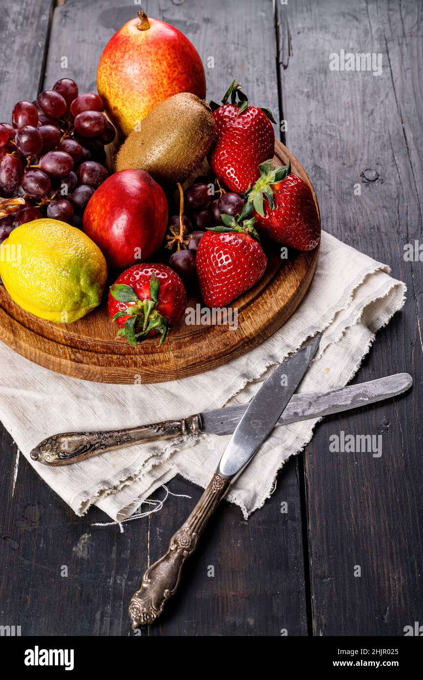 Frutta fresca e succosa assortita. Fragola, kiwi, mela, pera, banana, uva. Deliziosa frutta tropicale su sfondo di legno. Colazione salutare Foto Stock