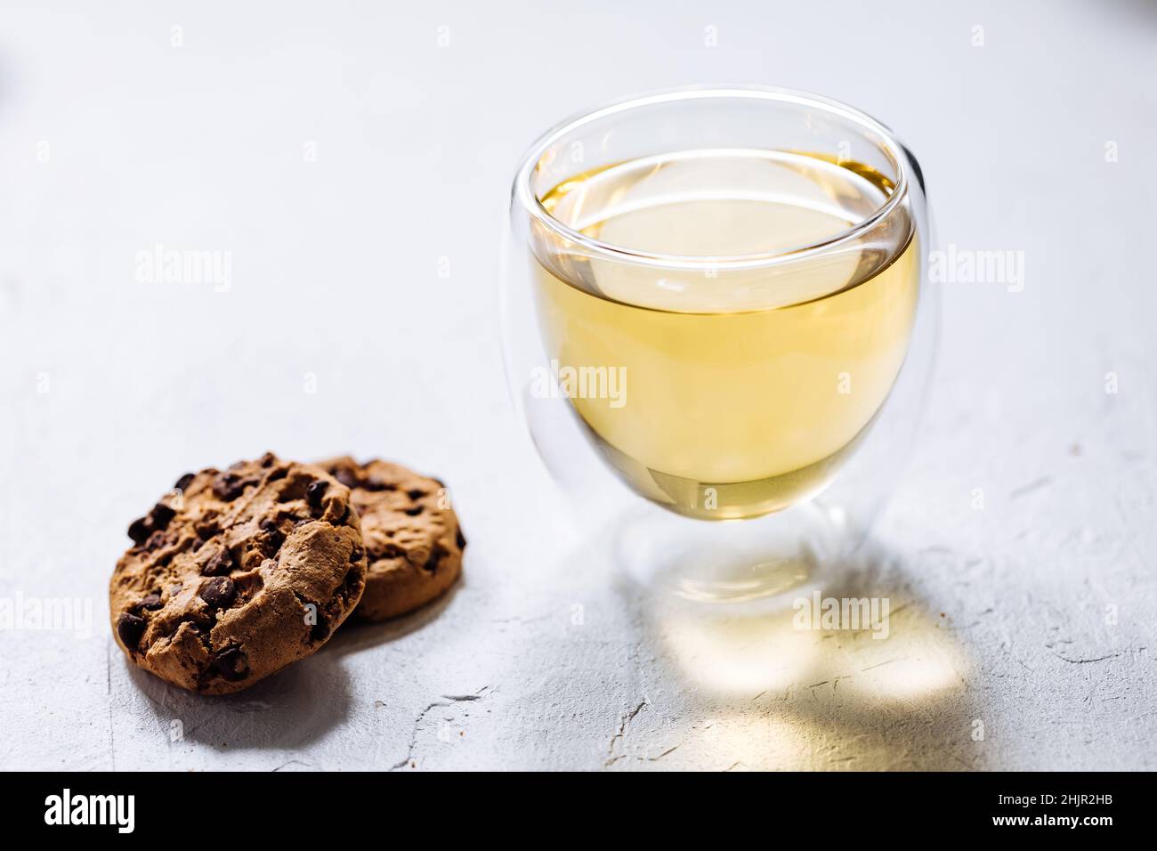 Biscotti con pezzetti di cioccolato e tè su sfondi diversi e in tazze diverse Foto Stock