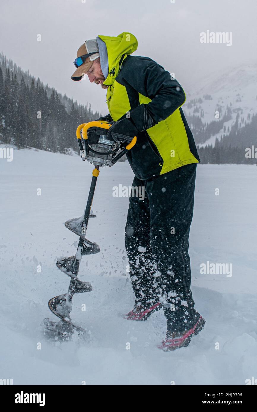 Uomo che perfora attraverso il ghiaccio Foto Stock