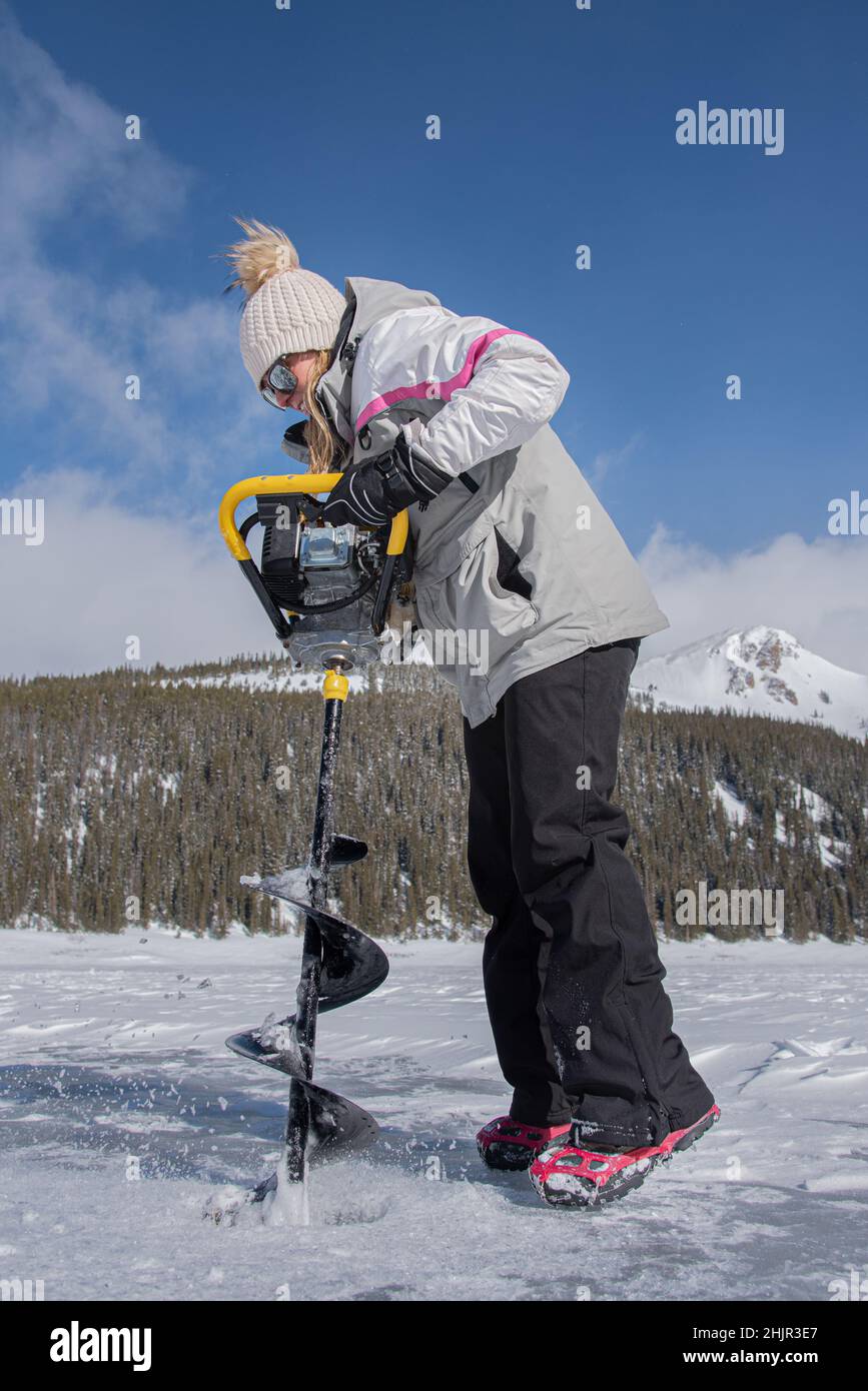 Donna che usa una trivella sul ghiaccio Foto Stock