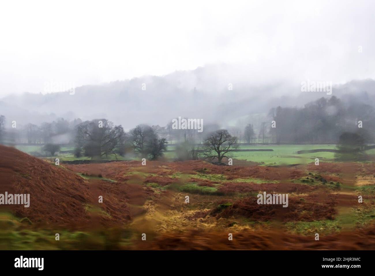 Una piccola valle appartata nel Lake District, Inghilterra, circondata da montagne le cui cime sono oscurate dalla nebbia Foto Stock