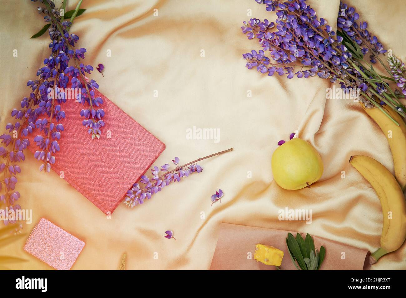 Lupini fiori viola, taccuino, decorazioni di mele su sfondo dorato. Concetto di picnic estivo. Posiziona per testo. Benessere vicinanza alla natura, concetto di auto-scoperta Foto Stock