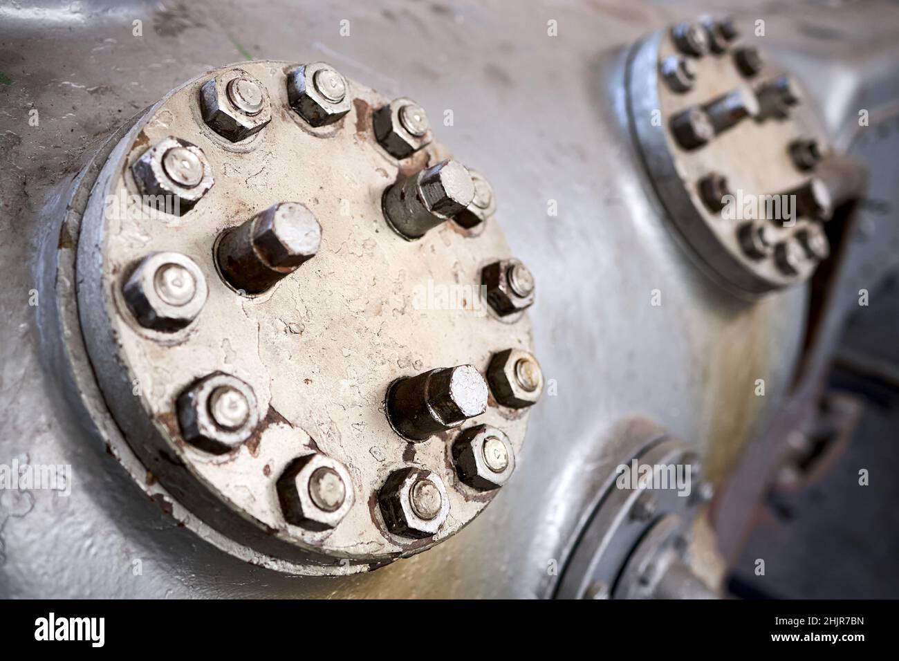 Due coperchi in metallo a vapore o botole piastra delle valvole del compressore in primo piano verniciata con vernice grigia imbullonata con viti prigioniere e dadi fondo con copyspace Foto Stock