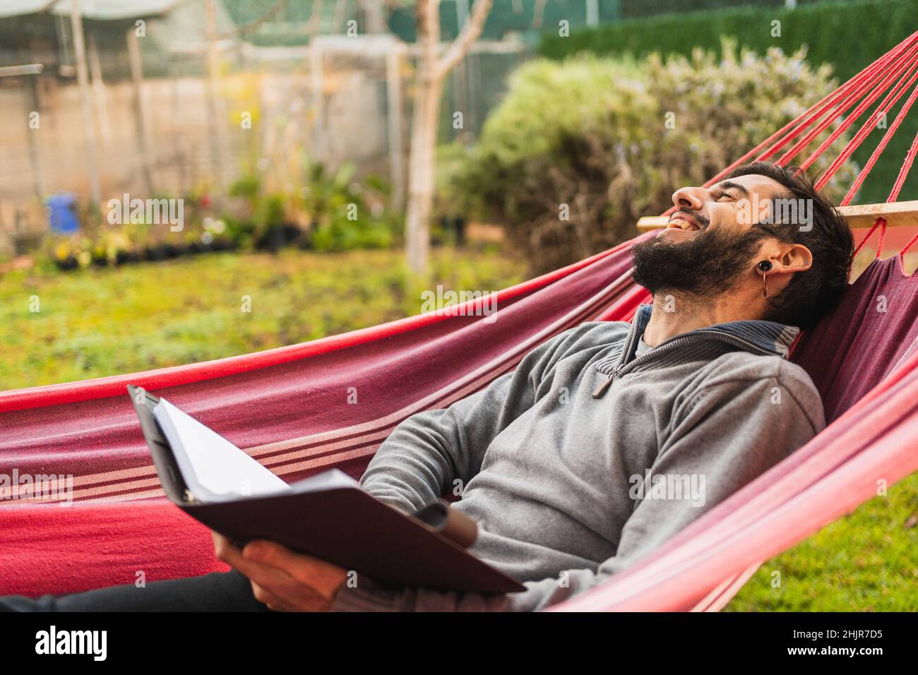 uomo di hipster rilassato in amaca lettura di un libro Foto Stock