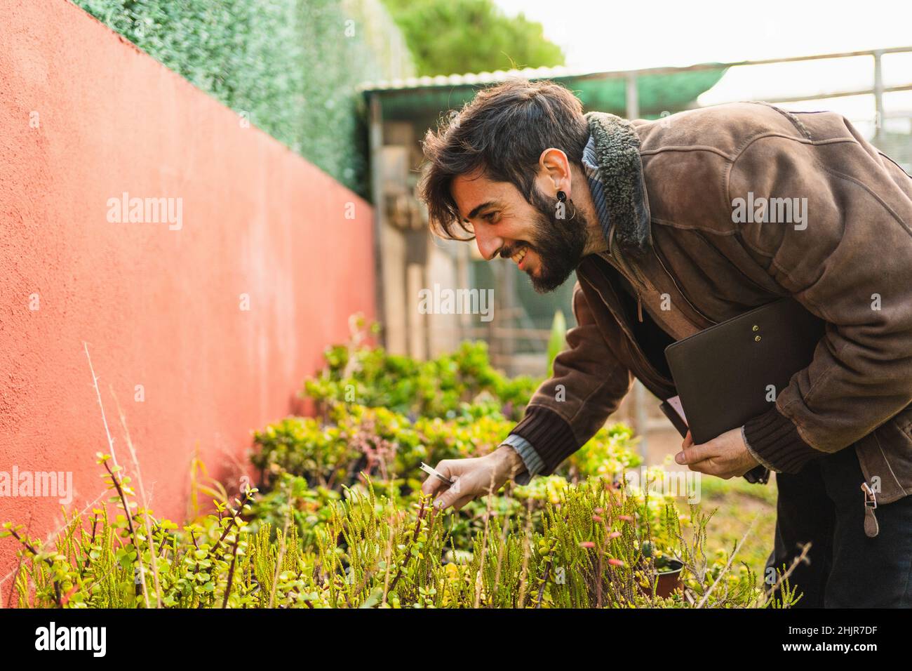 giardiniere sorridente che controlla la condizione e la crescita delle piante Foto Stock