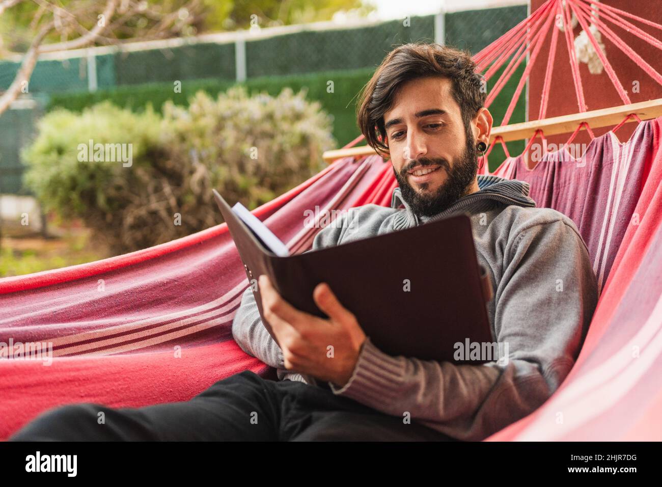 uomo di hipster rilassato in amaca lettura agenda Foto Stock