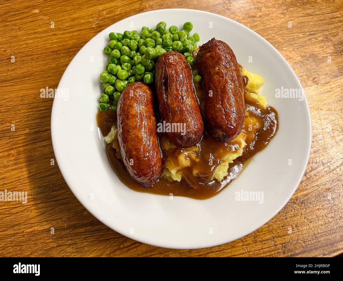 Cena con salsicce e schiacciate con piselli e sugo di carne Foto Stock