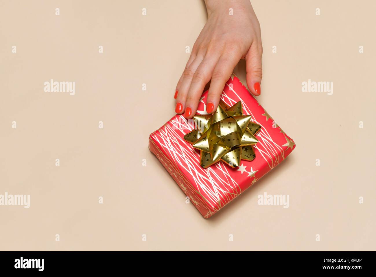 Una mano della donna raggiunge per una scatola regalo rossa con un arco giallo, un posto per il testo per copiare spazio. Foto Stock