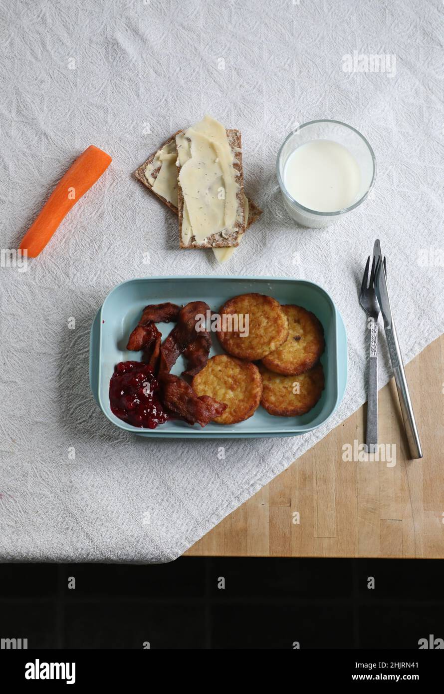 Gennaio è il mese povero non ufficiale dell'anno. Qui c'è qualcuno che mangia focaccine di patate, pancetta con carota, croccante svedese e un bicchiere di latte per pranzo. Foto Stock