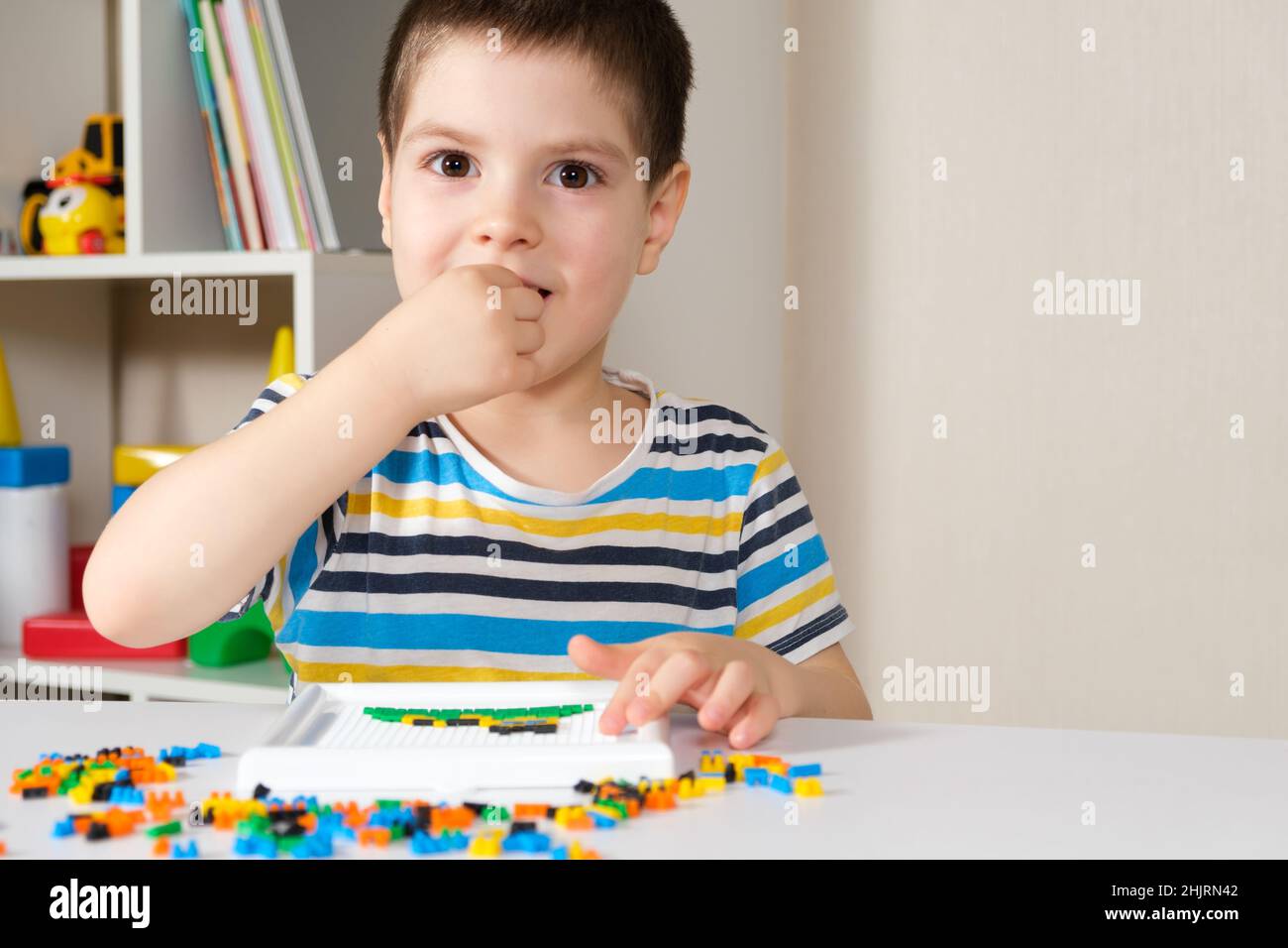 Il bambino gioca con mosaici, piccoli oggetti per bambini, prende un  piccolo dettaglio del mosaico in bocca. Pericolo di deglutizione di un  pezzo Foto stock - Alamy