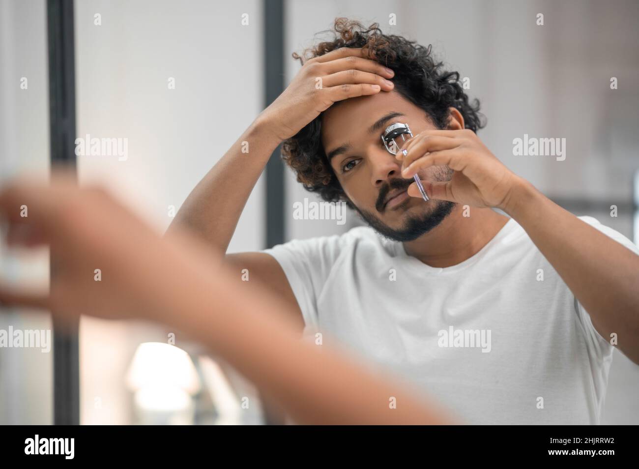 Il giovane si è concentrato a ricurlarsi le ciglia Foto Stock