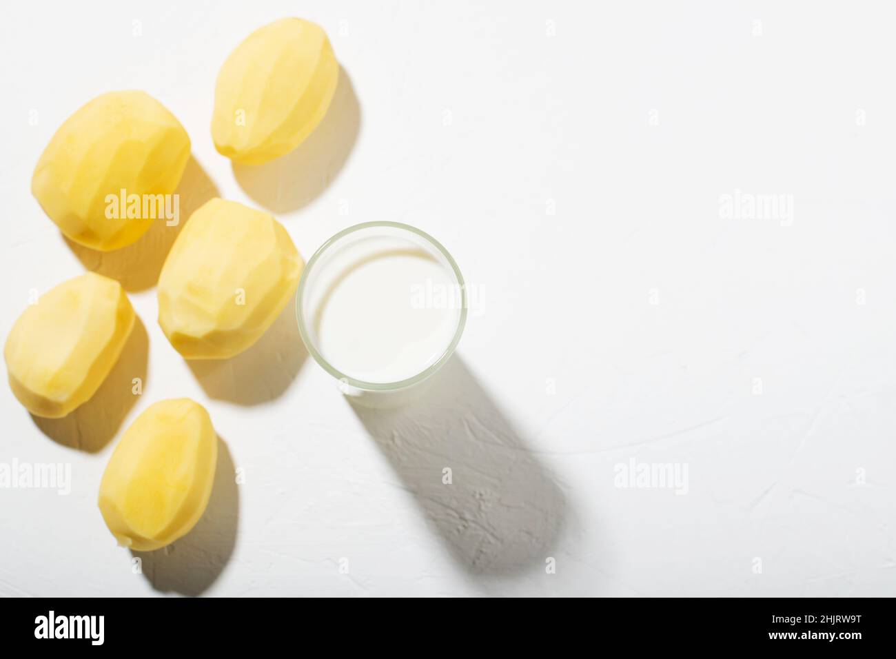 Latte di patate. Bicchiere con latte e patate crude su sfondo bianco. Vista dall'alto. Posiziona per testo. Foto Stock