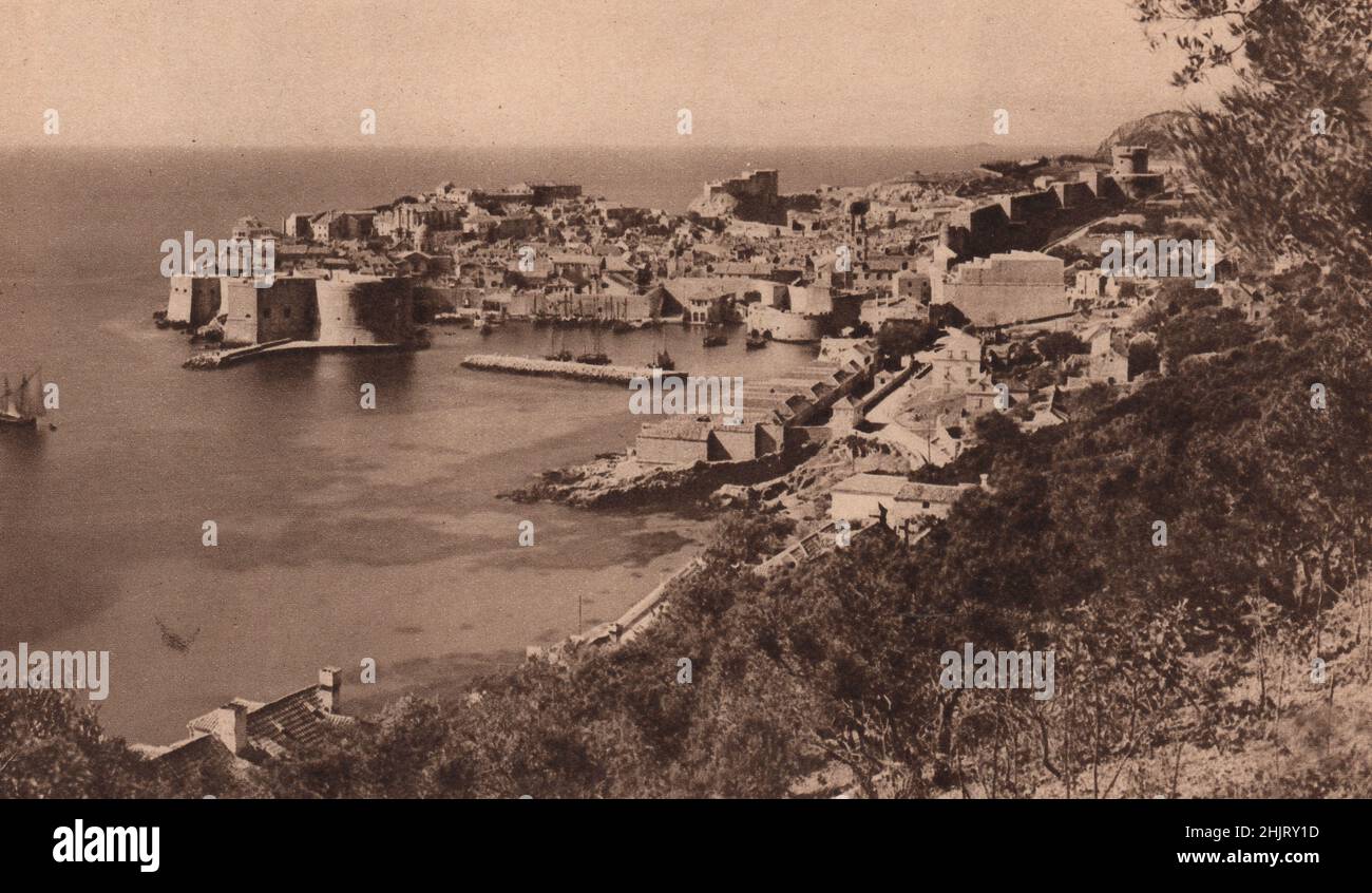 Bastioni e torri girano Ragusa dove copre un promontorio spinta nell'Adriatico. Dubrovnik. Croazia. Balcani (1923) Foto Stock