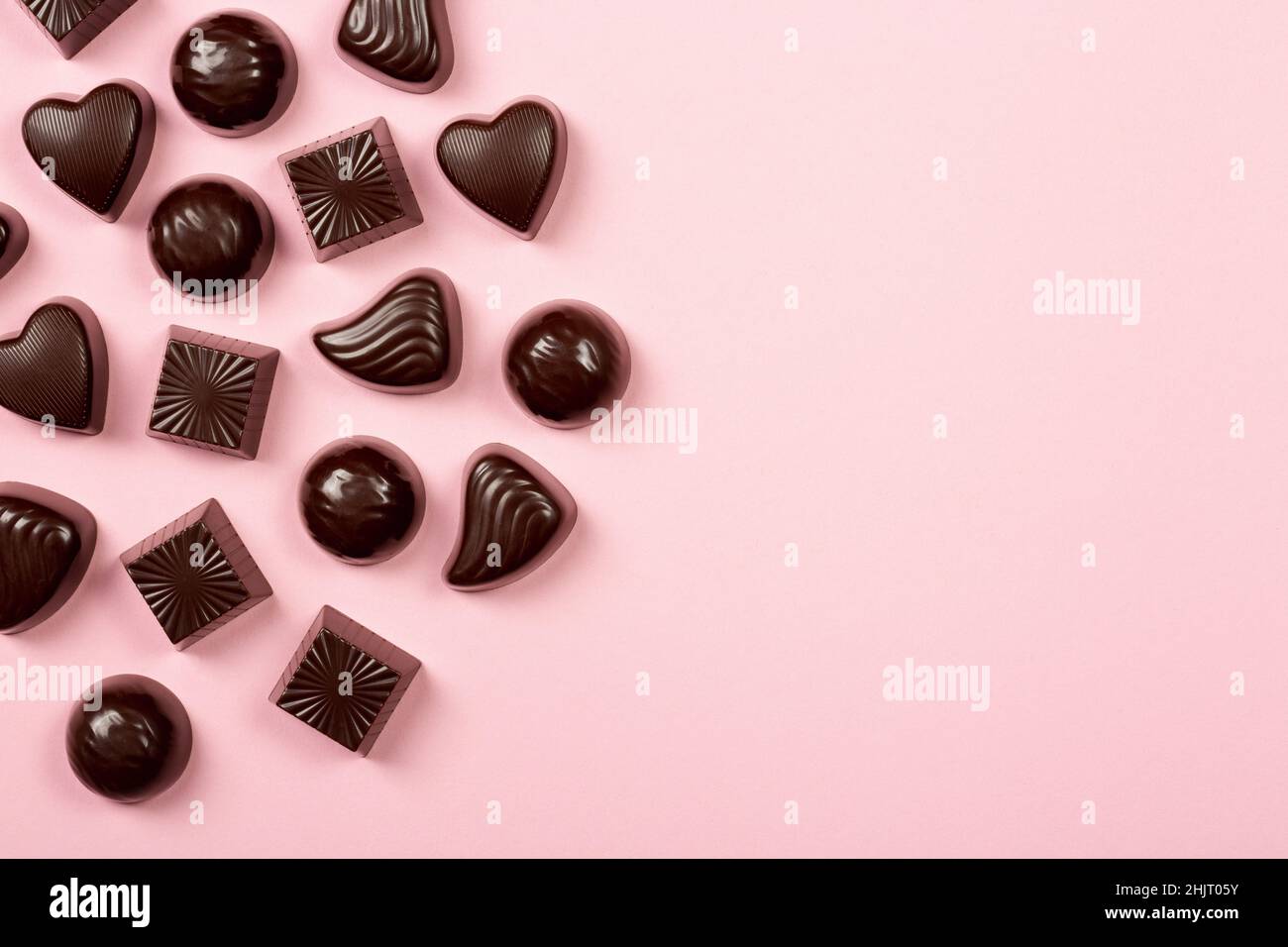 Assortimento di praline al cioccolato su sfondo rosa, piatto, vista dall'alto con spazio copia Foto Stock