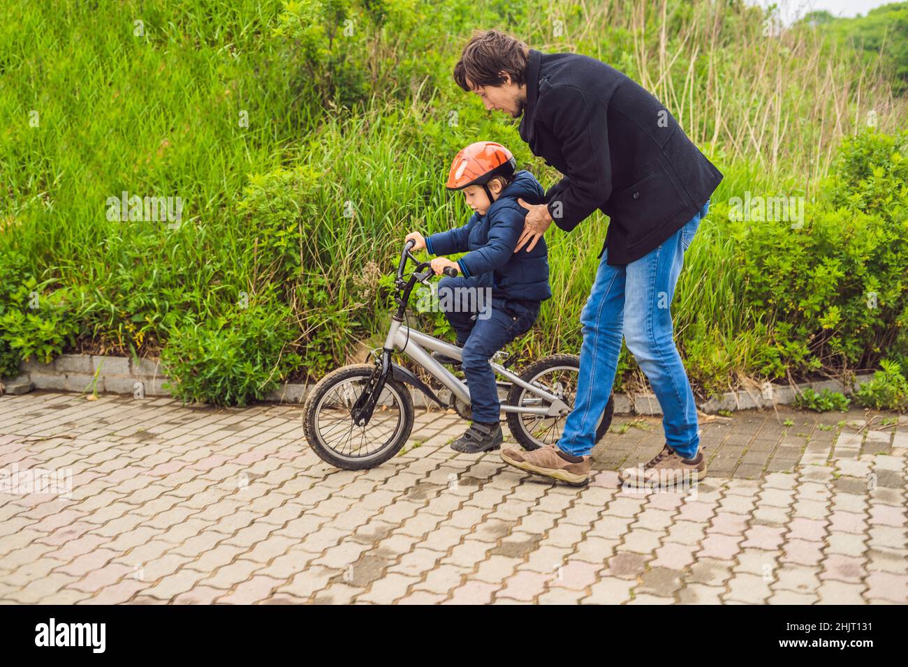 Papà insegna il figlio per un giro in bici nel Parco Foto Stock