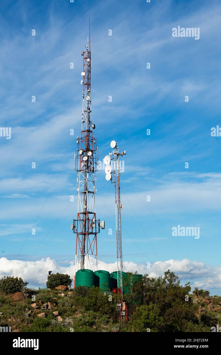 Vista di una trasmissione, telecomunicazioni, torre di trasmissione, antenna e parabola satellitare con sfondo blu cielo. Foto Stock