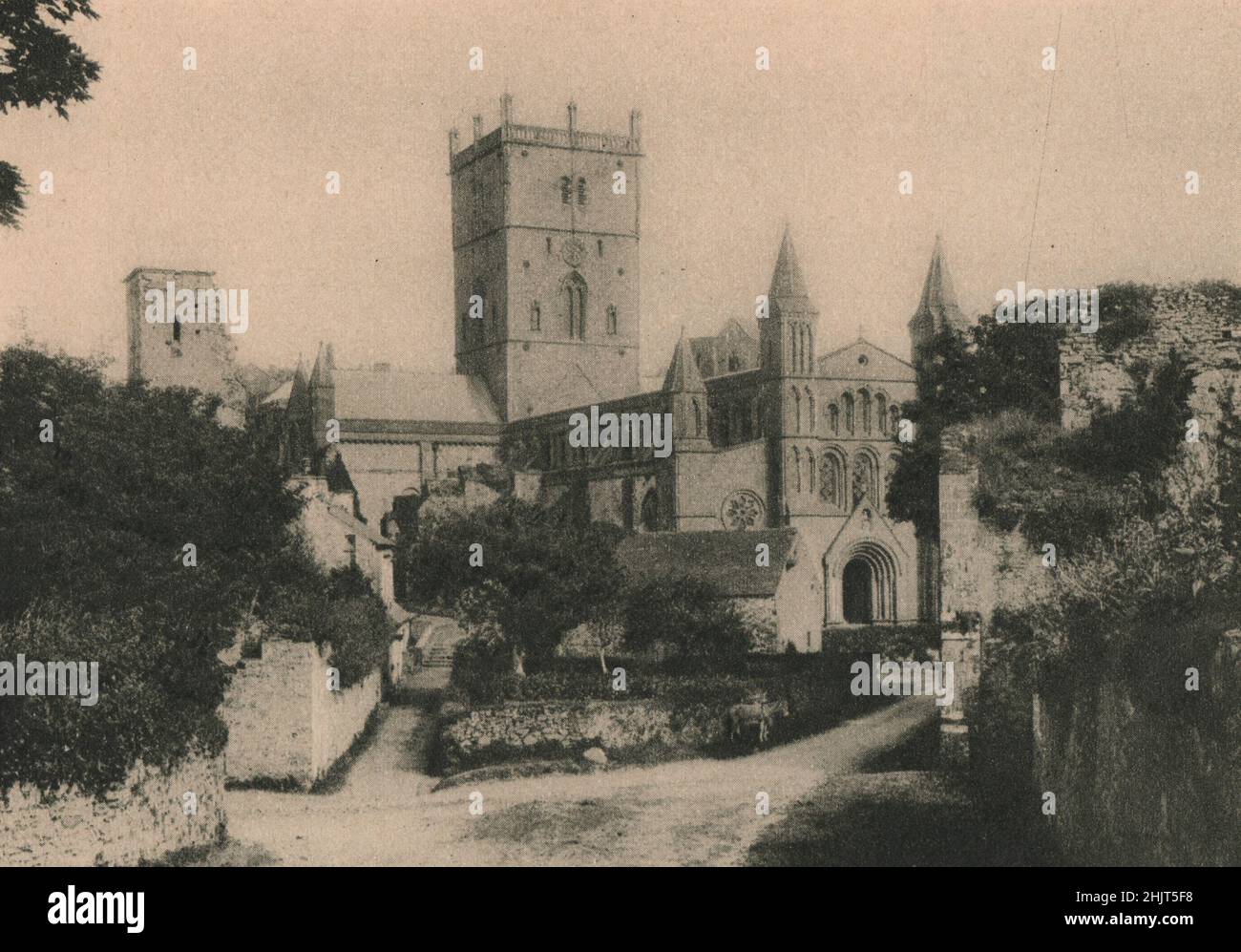 Circondata da grandi rovine in un villaggio che una volta era una città, la cattedrale di San David embattled sorge da una valle sassosa del Pembrokeshire. Galles (1923) Foto Stock