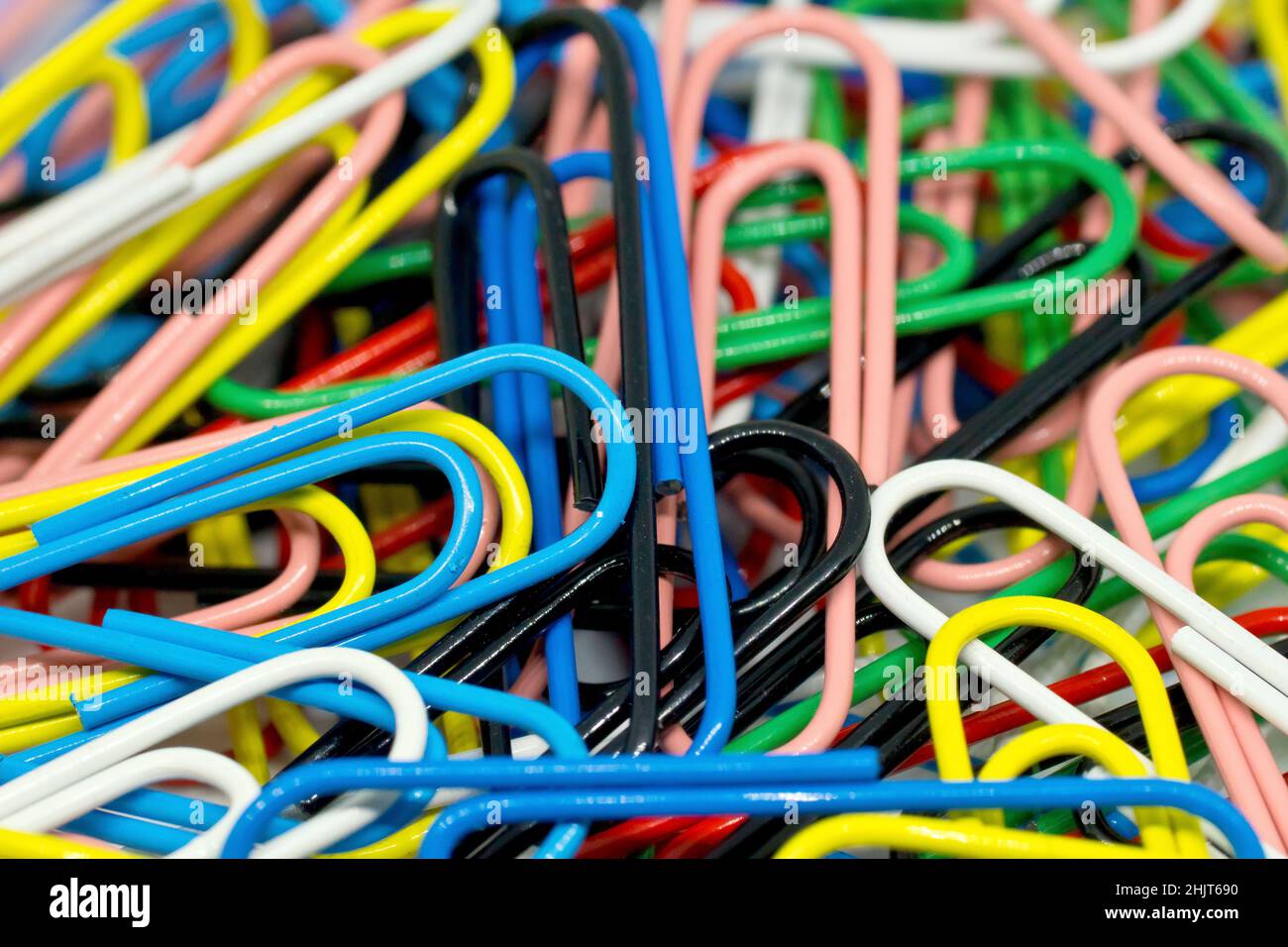 Primo piano astratto vita morta di una massa disorganizzata di graffette colorate. Foto Stock