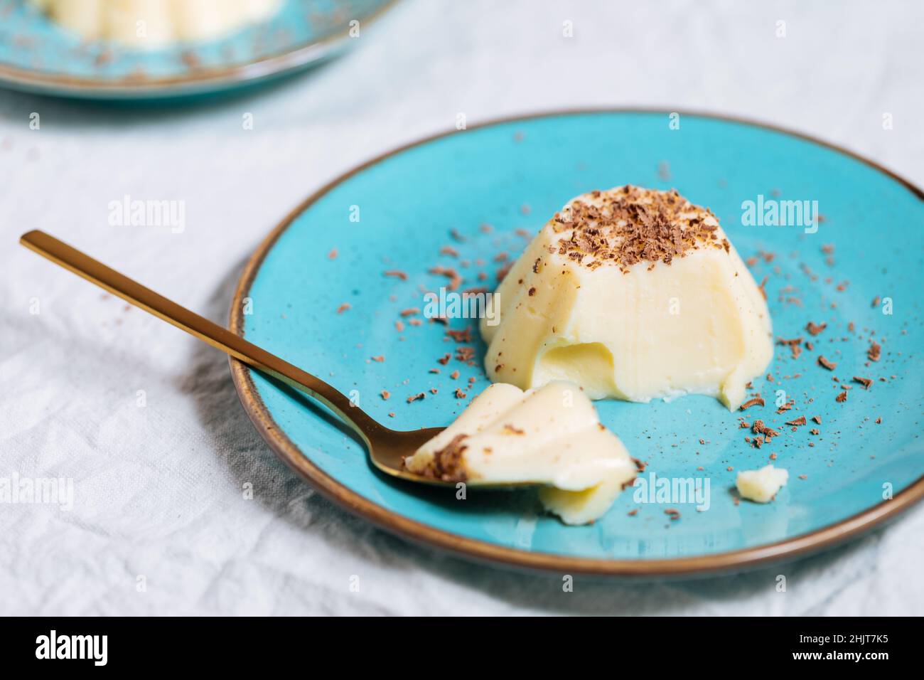 Budino di vaniglia su piastra di porcellana blu con briciole di cioccolato sulla parte superiore. Sfondo luminoso Foto Stock