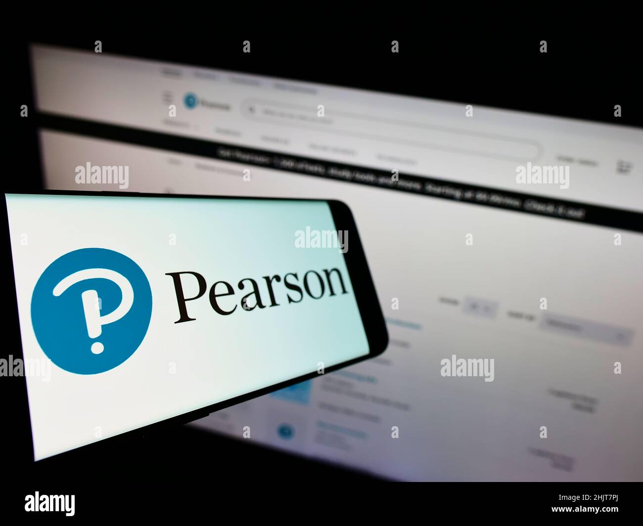 Telefono cellulare con logo della società editoriale britannica Pearson plc sullo schermo di fronte al sito Web aziendale. Mettere a fuoco sulla sinistra del display del telefono. Foto Stock