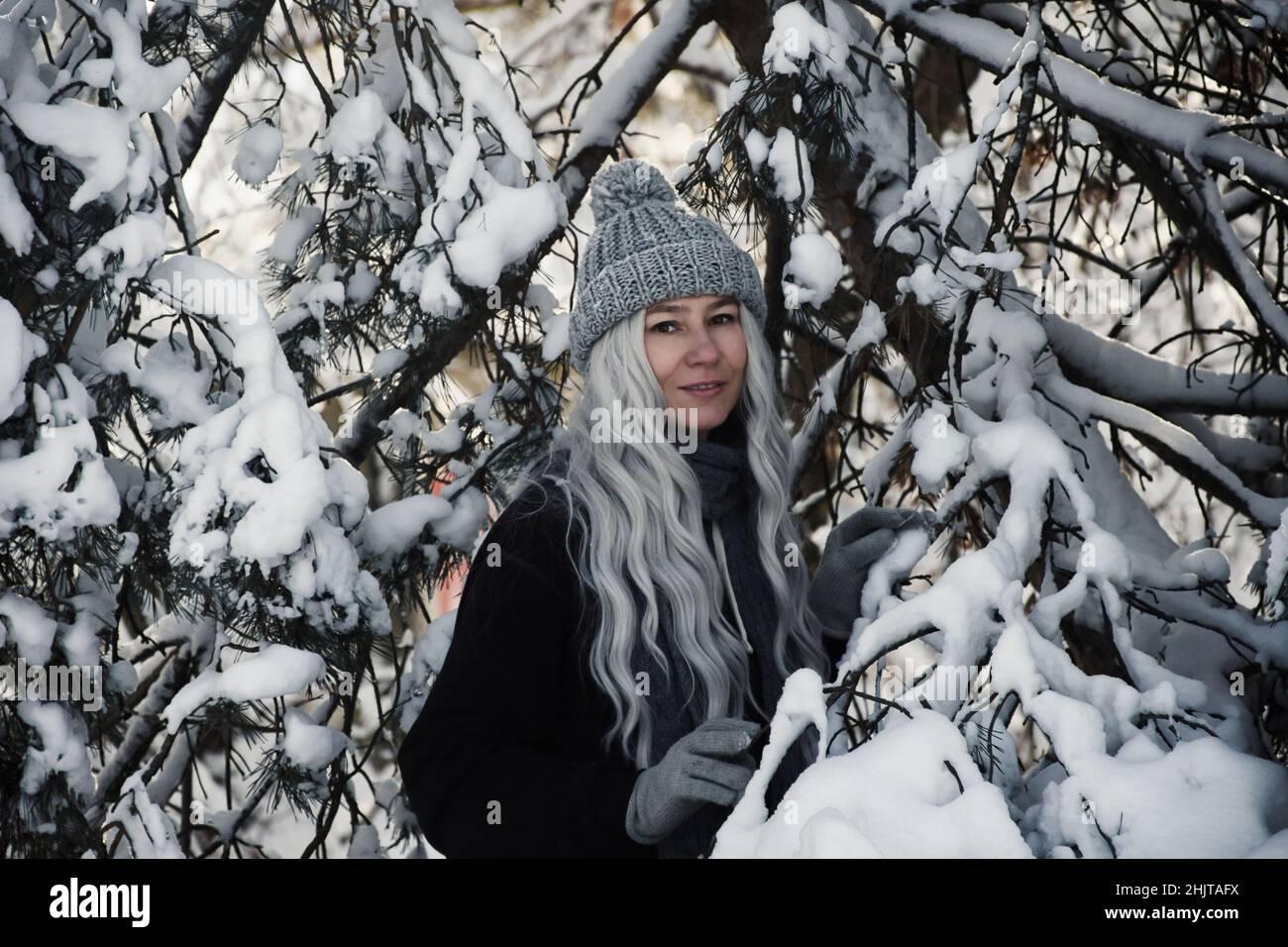 la donna bionda gioisce in inverno in una foresta innevata nel pomeriggio. Foto Stock