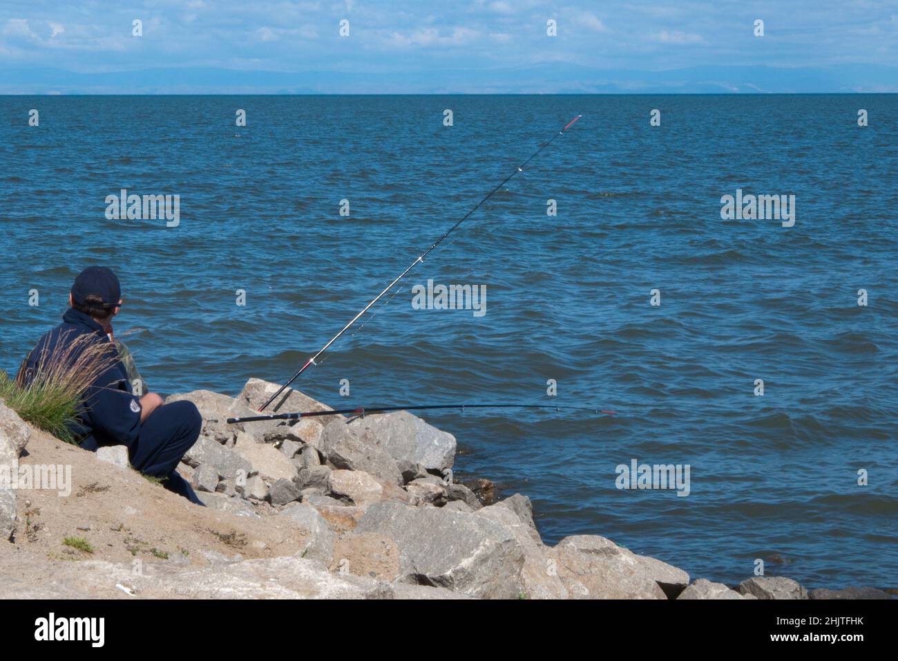 L'uomo irriconoscibile pesca sul lago Baikal. Visto dalla schiena. Russia. Il Lago Baikal si trova in una valle di rift, creata dalla zona di rift Baikal, dove l'orecchio Foto Stock