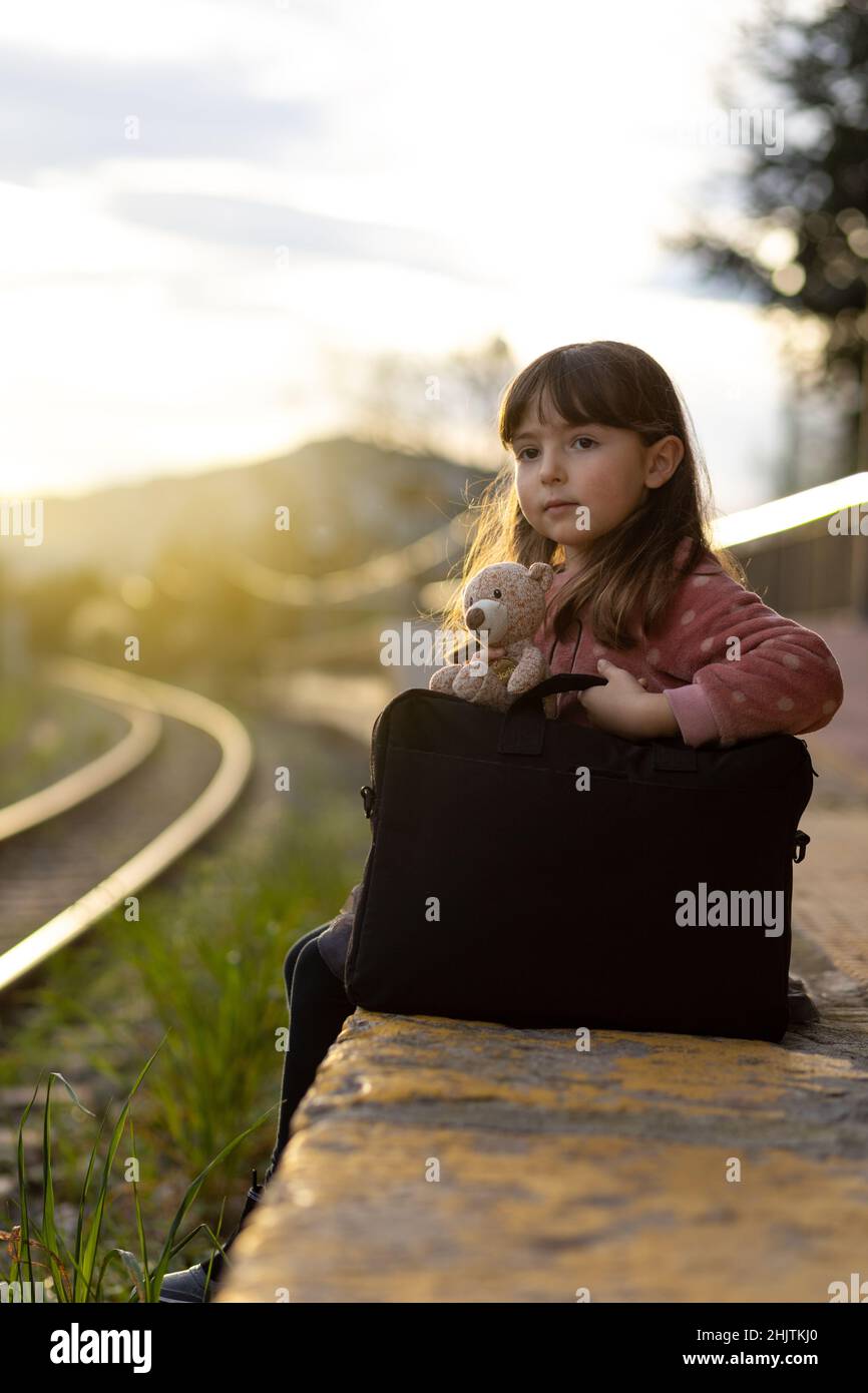 Ragazza in attesa del treno seduto sul bordo della piattaforma Foto Stock