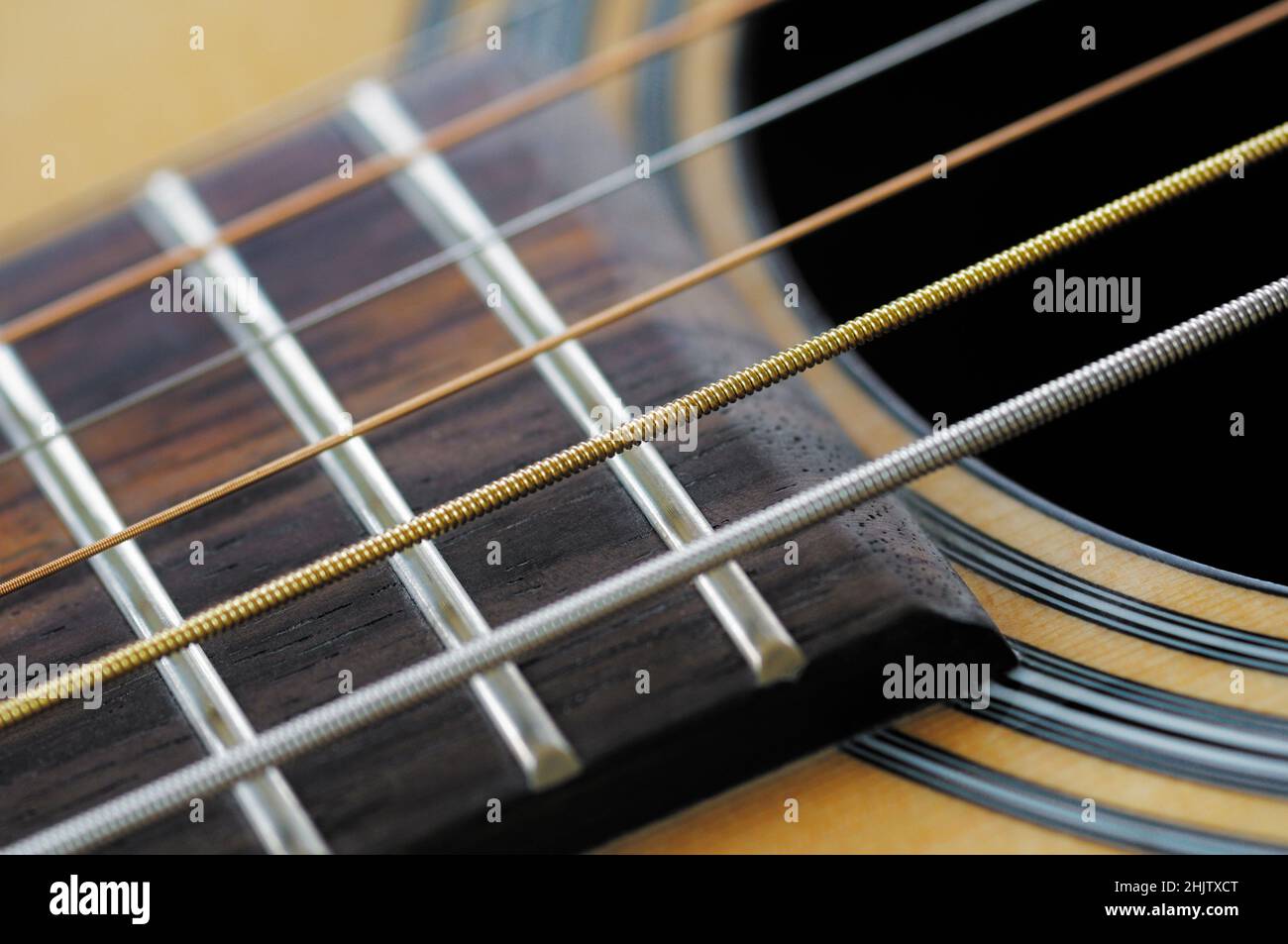 Primo piano dettaglio di corde e tasti di chitarra sulla tastiera (o tastiera) di una chitarra acustica. Foto Stock