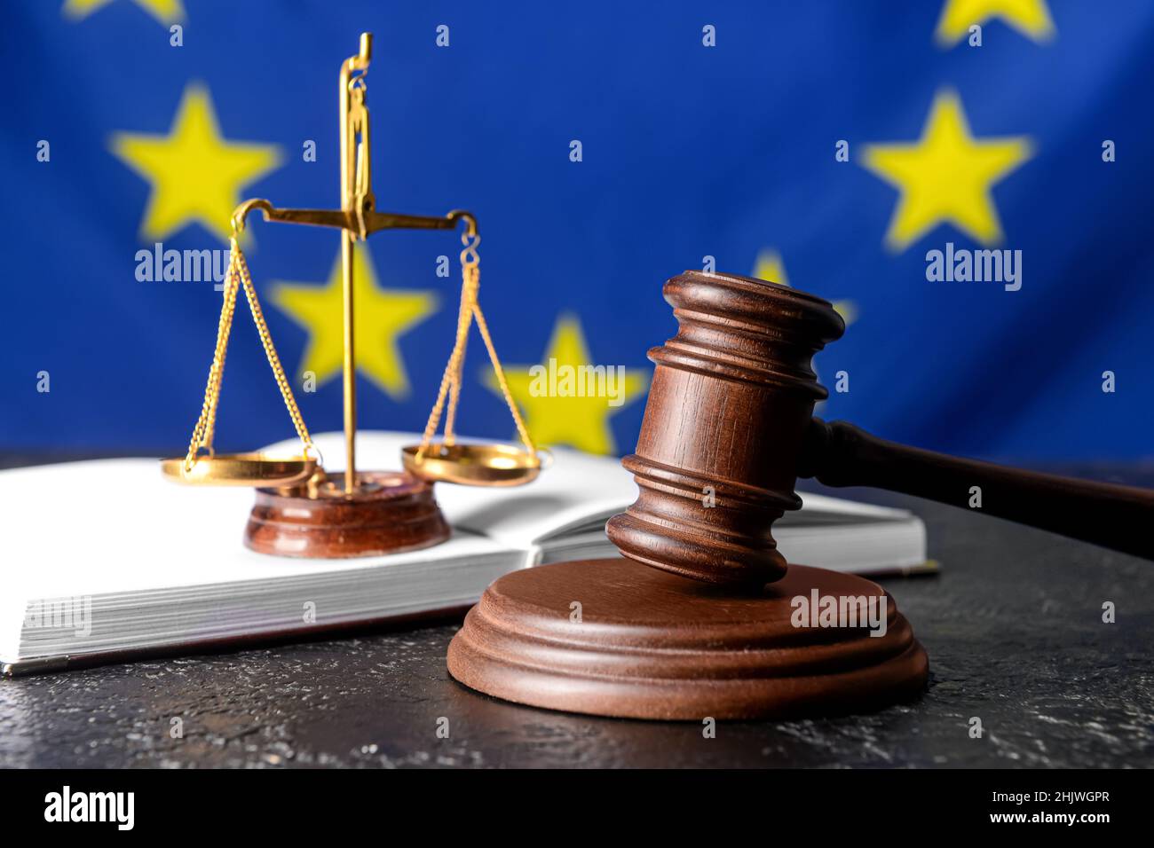 Gavel di giudice con scala di giustizia e libro contro la bandiera dell'Unione europea Foto Stock