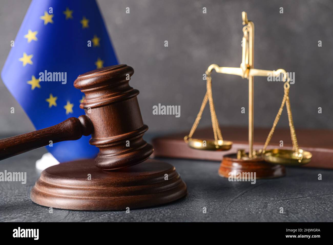 Gavel di giudice con scale di giustizia e bandiera dell'Unione europea su sfondo scuro Foto Stock