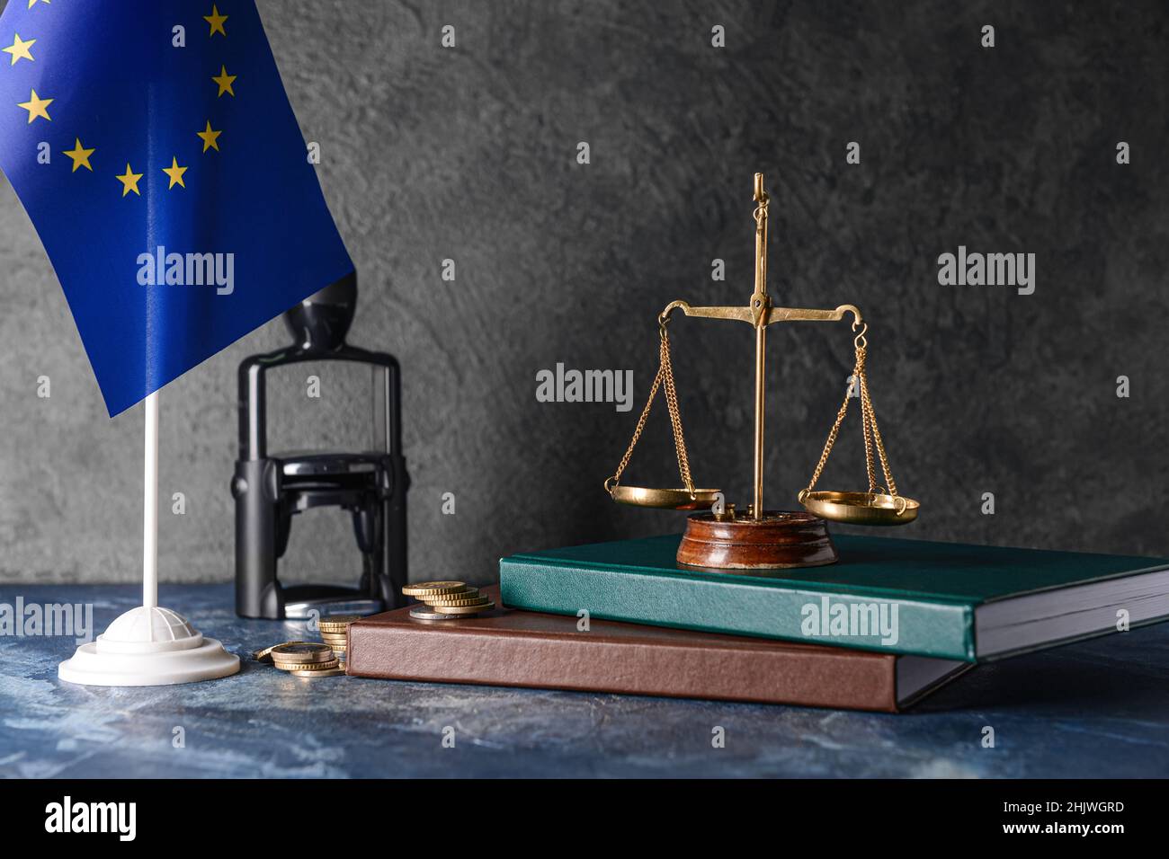 Scale di giustizia con libri, monete e bandiera dell'Unione europea su sfondo scuro Foto Stock