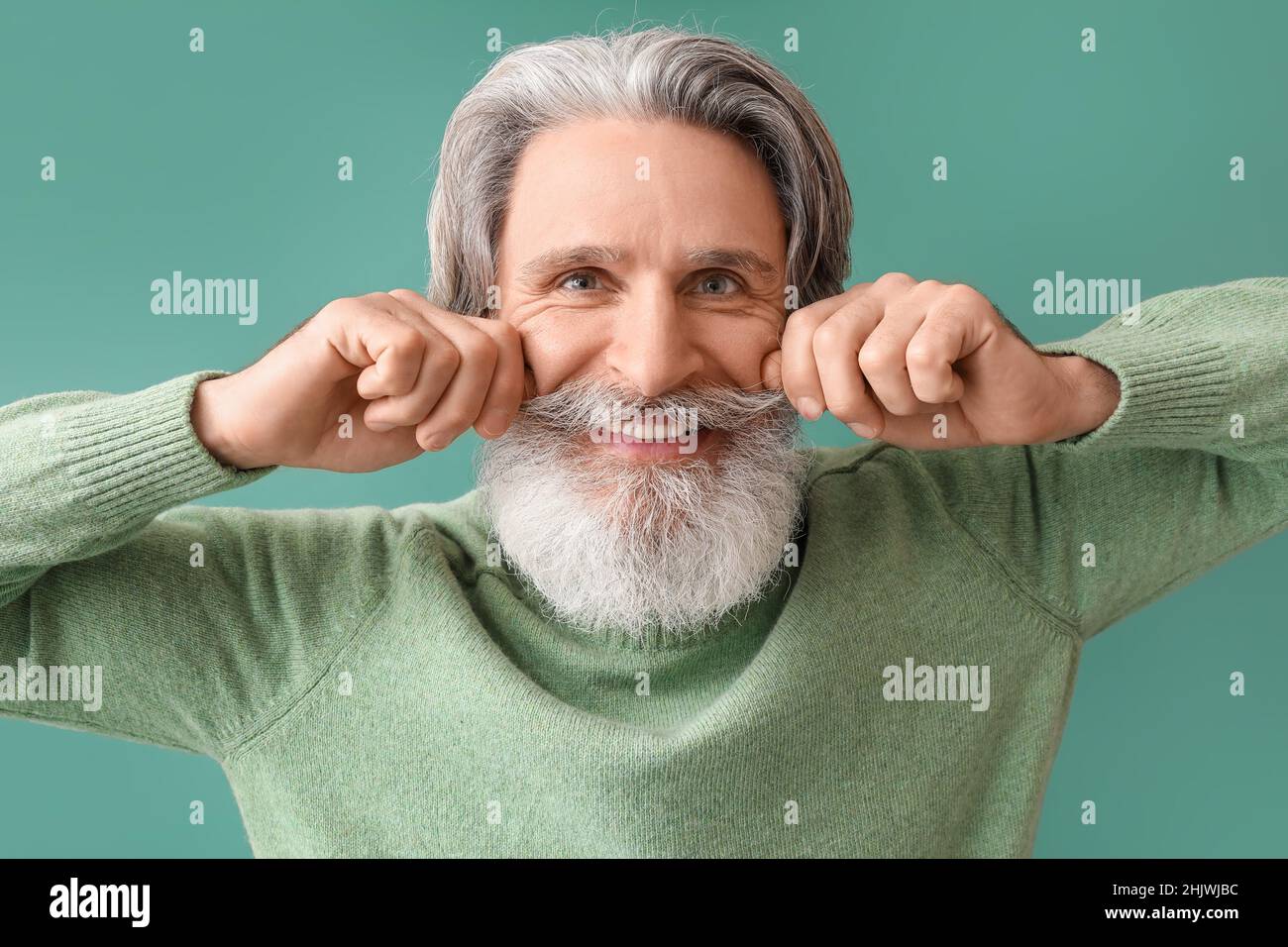 Uomo anziano felice in maglia maglione su sfondo verde Foto Stock