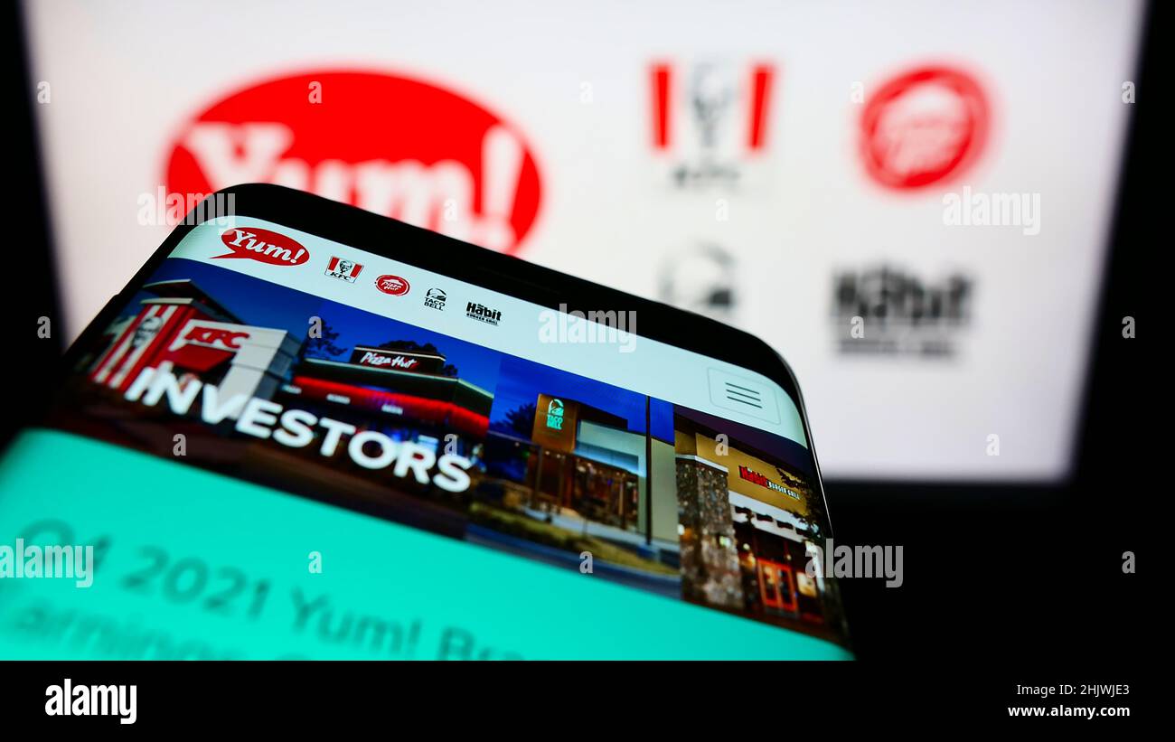 Telefono cellulare con pagina web della società americana di fast food Yum! Brands Inc. Sullo schermo davanti al logo aziendale. Concentrarsi sul centro del display del telefono. Foto Stock