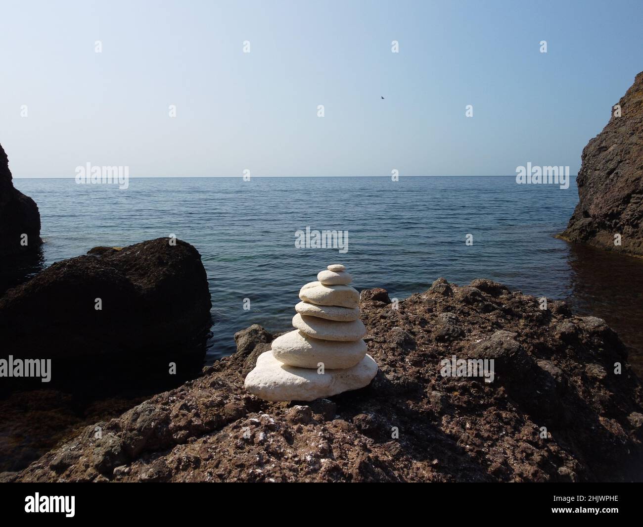 Piramide di ciottoli bilanciata sulla spiaggia nelle giornate di sole e cielo limpido al tramonto. Il mare d'oro bokeh sullo sfondo. Fuoco selettivo, pietre zen sulla spiaggia di mare Foto Stock