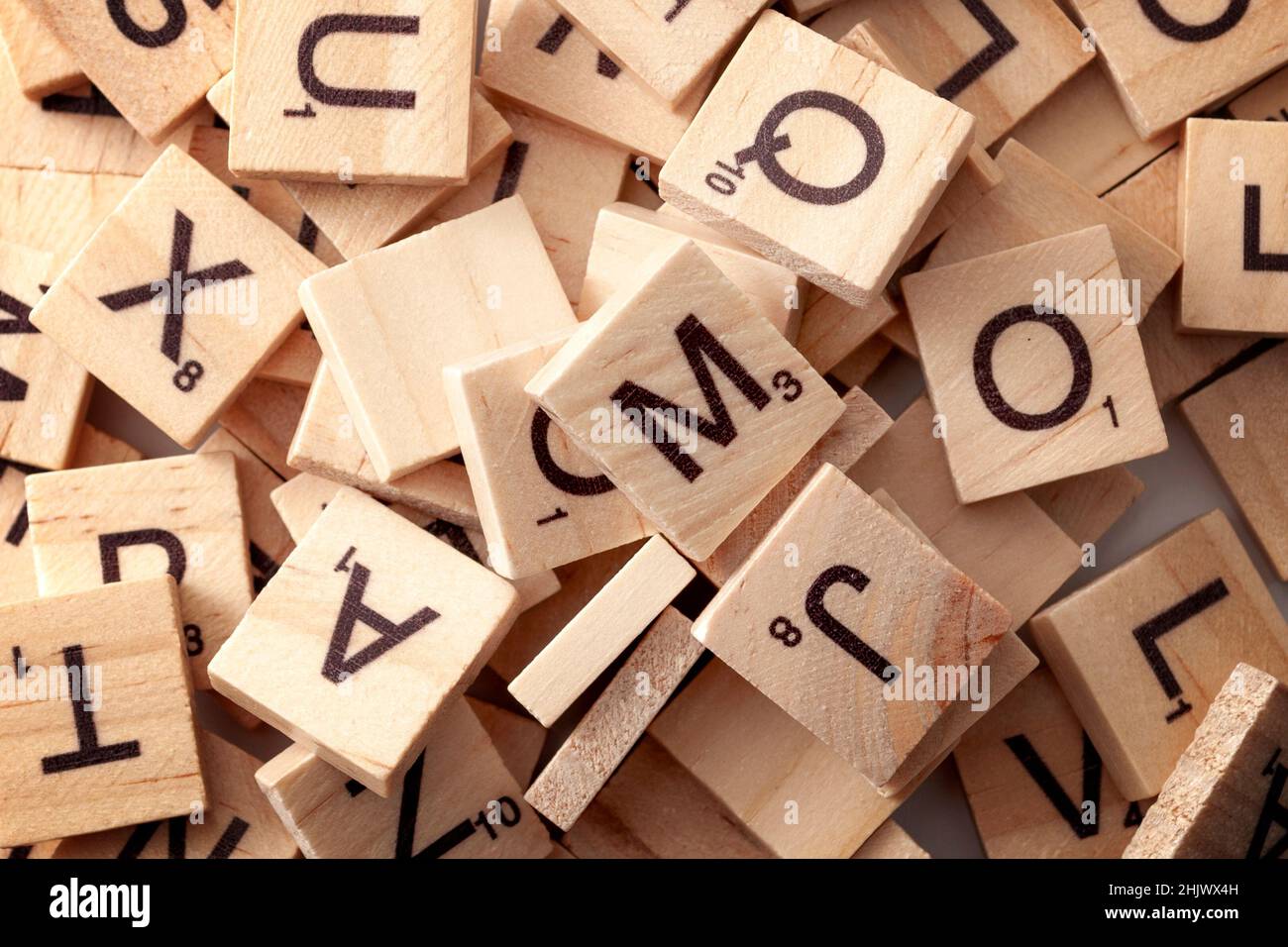 Gioco educativo, brainteaser e tema di concetto di gioco da tavolo con diverse piastrelle di legno con lettere e numeri utilizzati per scrivere le parole nei giochi di parole Foto Stock